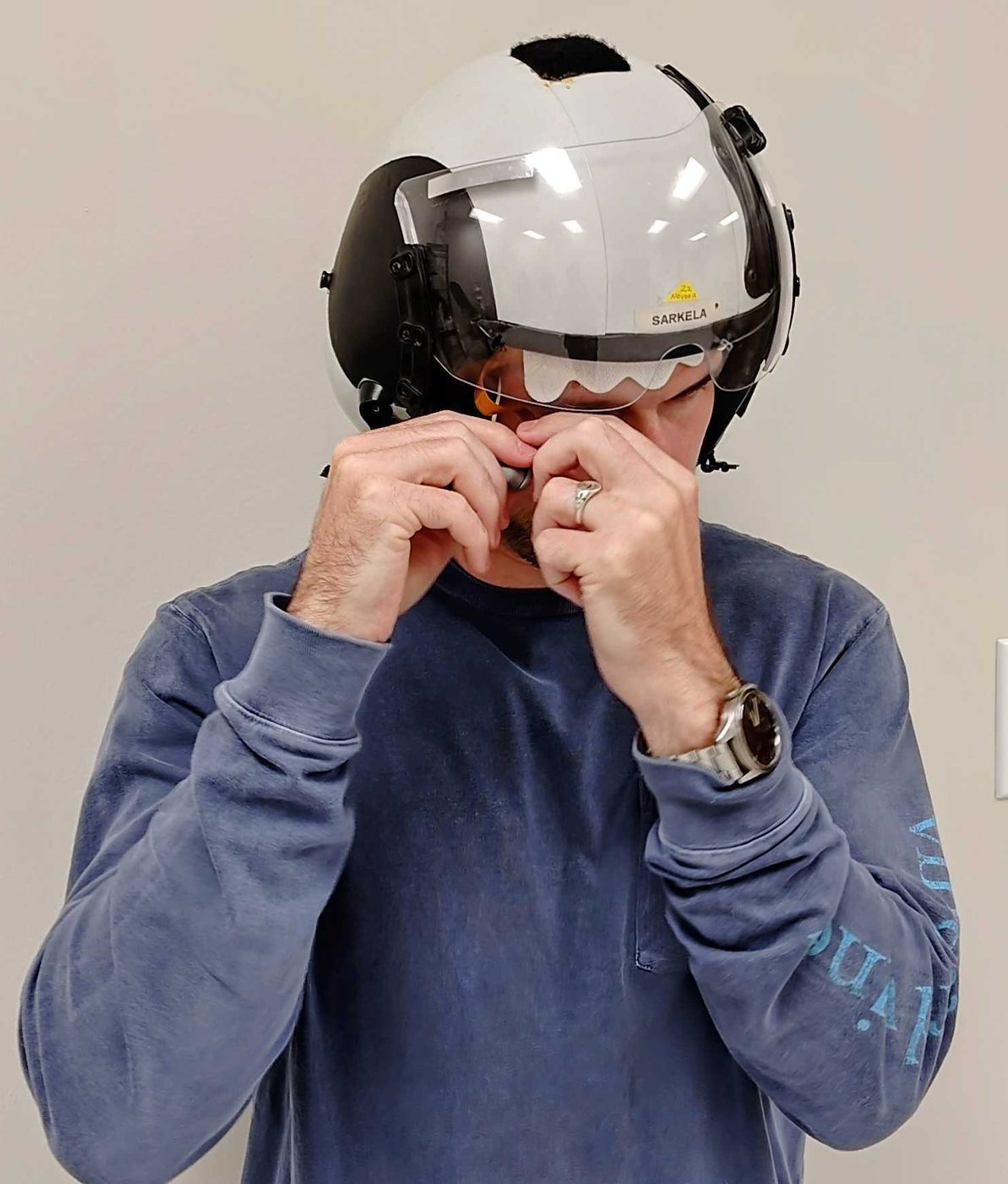 A person in a flight helmet fitting a helmet-compatible sensor