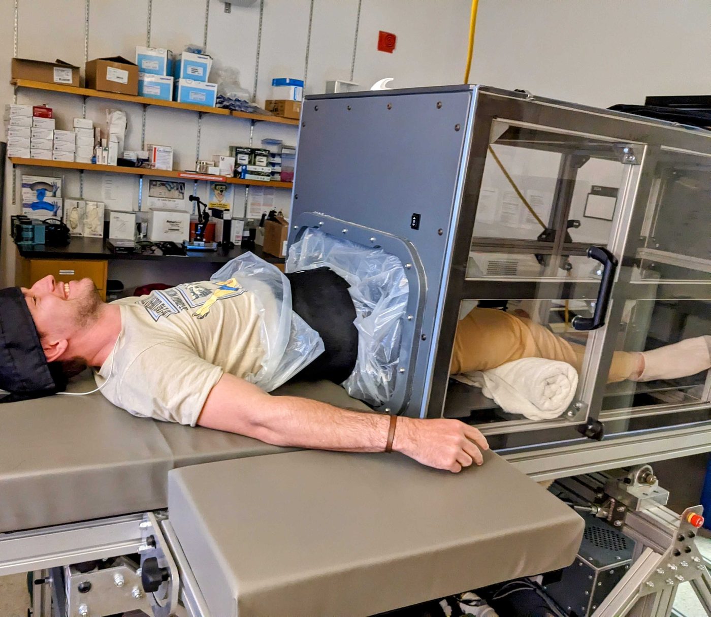Thibault lying on a table with his lower body sealed inside a lower body negative pressure chamber. Lower body negative pressure, a laboratory model of blood loss used in hemorrhage research.